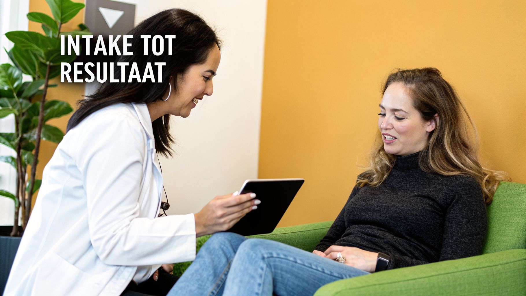 Een specialist in een witte jas toont een tablet aan een glimlachende cliënt tijdens een intakegesprek.