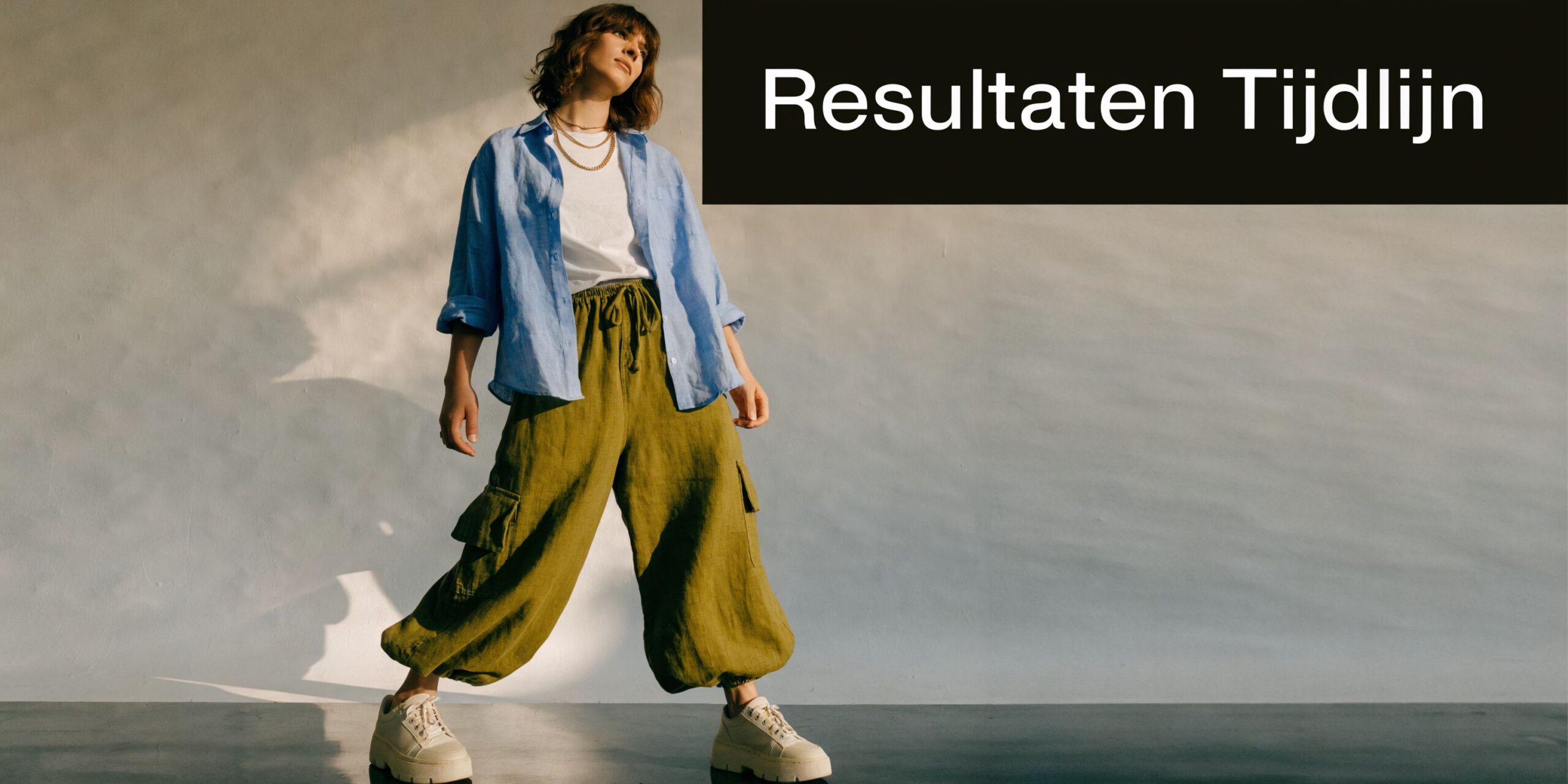 Een stijlvolle persoon in casual kleding staat zelfverzekerd in een studio voor de Resultaten Tijdlijn presentatie.