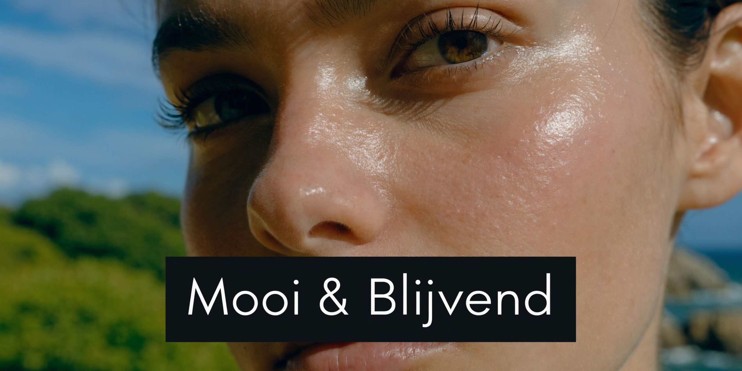 Close-up van een gezicht met een stralende huid tegen een achtergrond van natuur en de blauwe lucht.