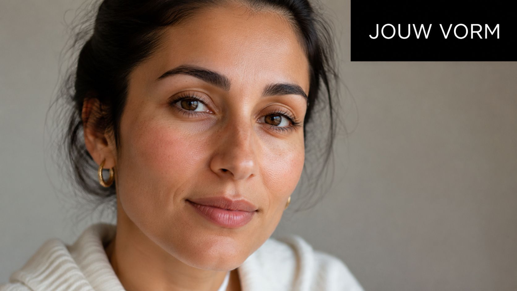 Een close-up portret van een vrouw met natuurlijk gevormde wenkbrauwen kijkend in de camera