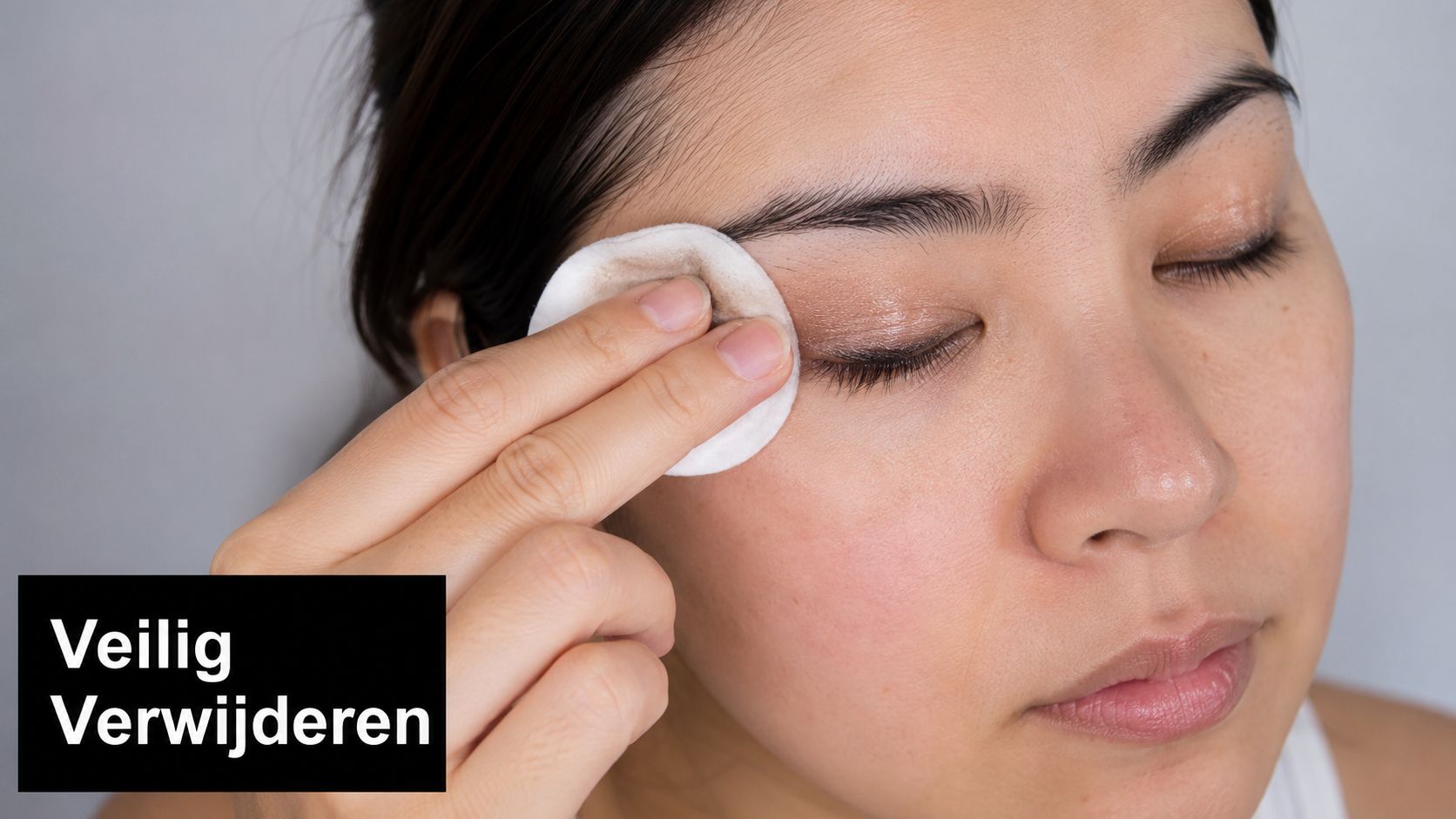 Een vrouw verwijdert voorzichtig oogmake-up van haar ooglid met een zacht wattenschijfje en een reinigingsmiddel.